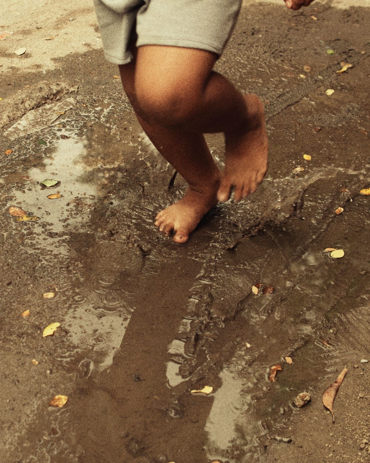 A child's bare feet splashing in a puddle