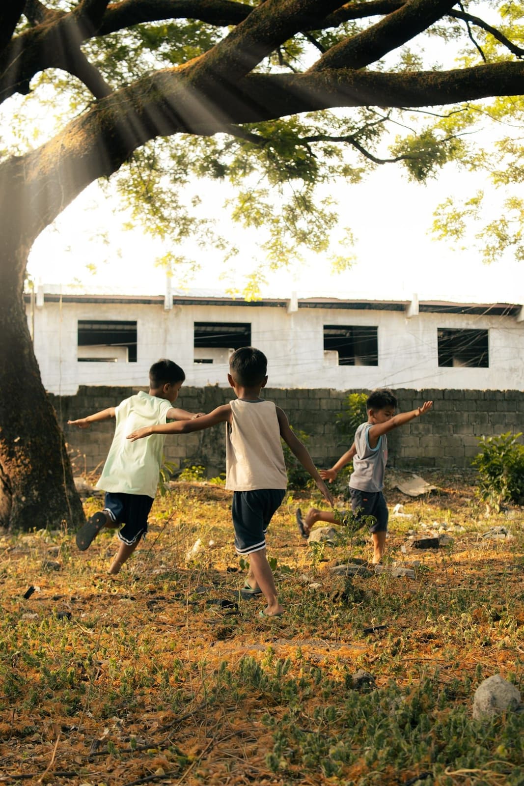 Three boys running barefoot across a field