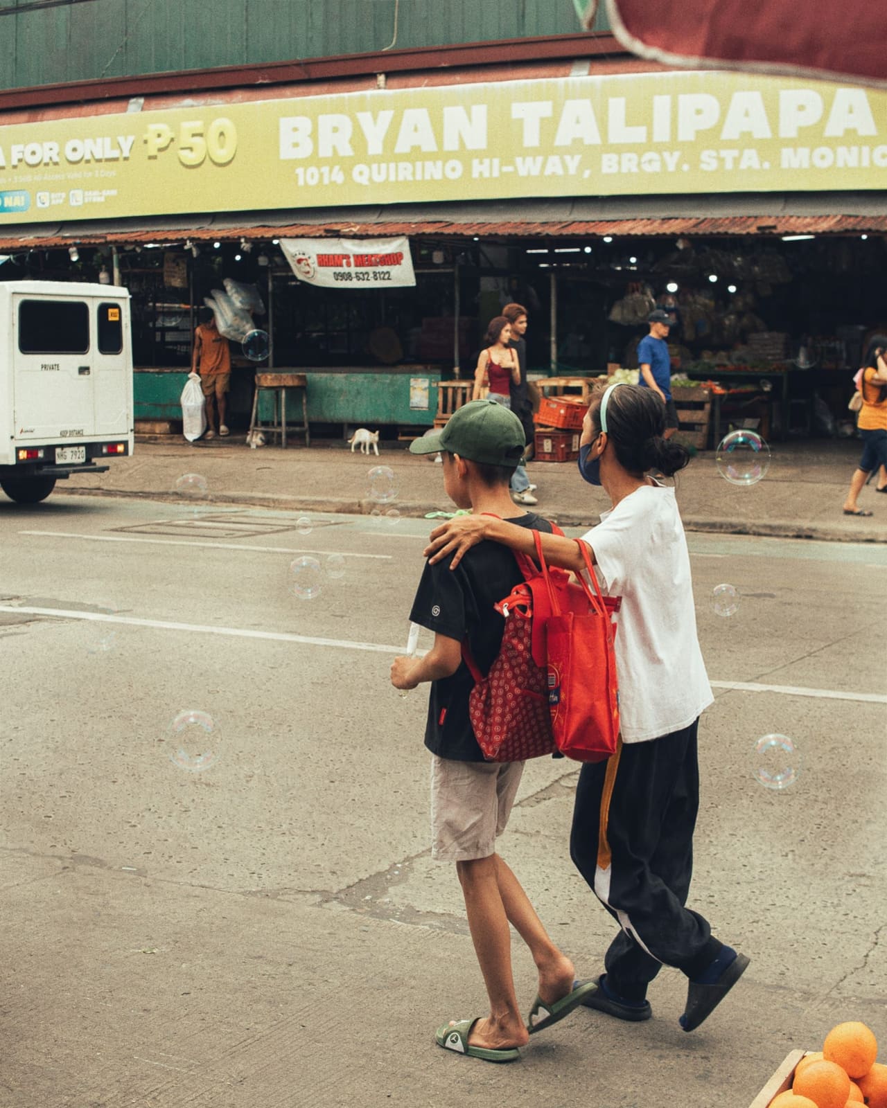 Two boys walking past a talipapa market